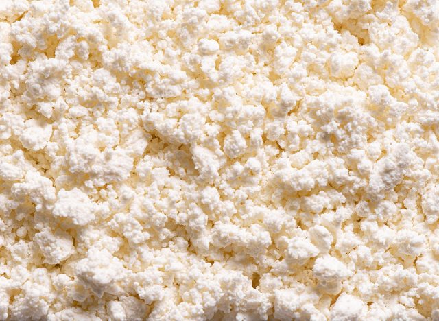 Cottage cheese or fresh milk curd as background close up. Homemade cottage cheese texture.