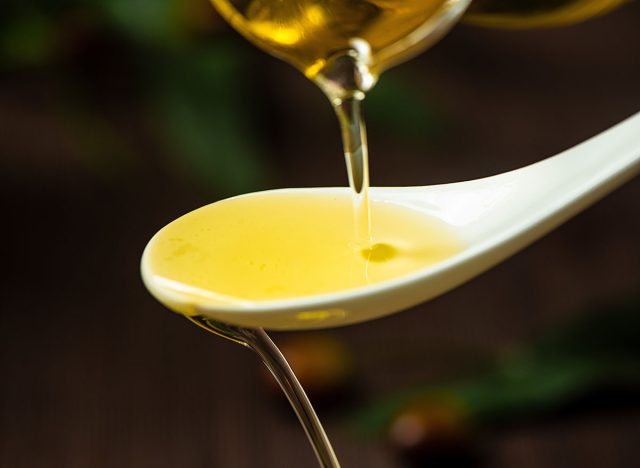 pouring olive oil in a spoon on table.