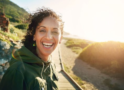 Portrait, morning and walk with woman, smile and fitness with sunshine, workout and nature. Face, person and runner with healthy routine, lens flare and vacation with exercise, warm up and training