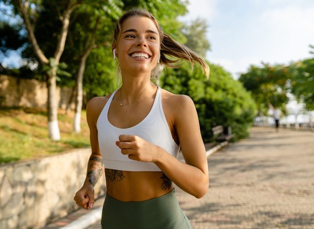 pretty young blond smiling woman doing sport exercises running jogging in morning park, skinny fit in sports wear outfit leggings and top, summer health motivation, strong body, hot