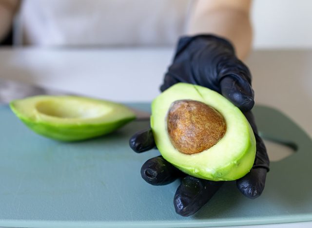 A girl holding an avocado in close-up. Avocado with a bone. Slicing avocado