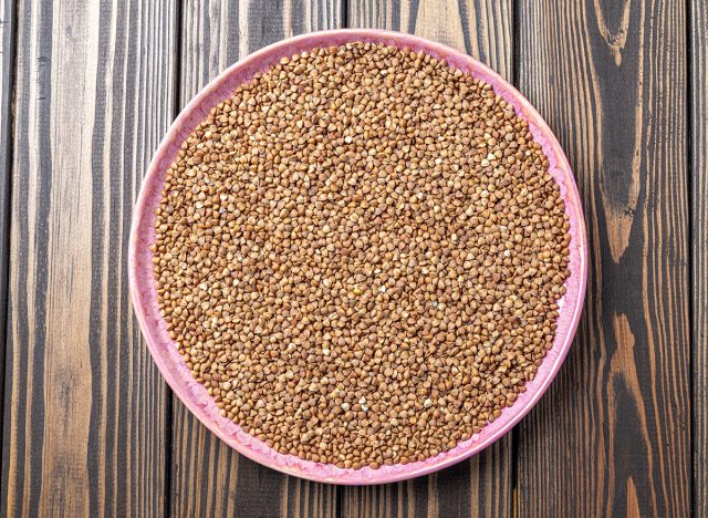 Buckwheat Grains on Plate on Wooden Background, Top View, Copy Space.Hulled kernels of buckwheat grains close up. Food background.