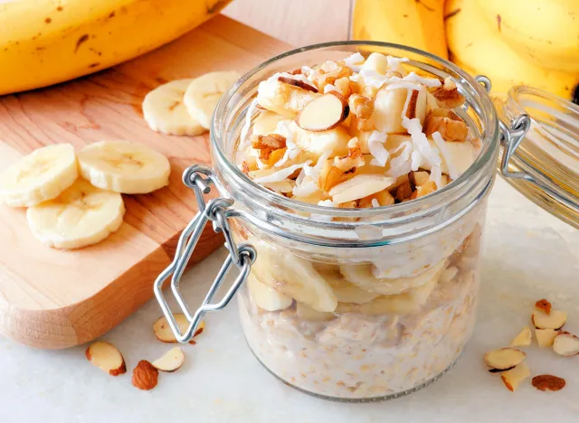 Overnight oats with bananas and nuts in snap lid glass jar on white marble