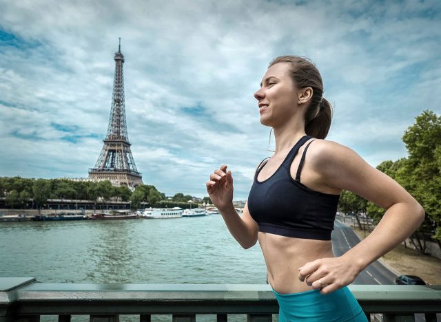 Running woman. Runner jogging at summer day. Female fitness model training outside in Paris City with beautiful view on Eifel Tower - symbol of Paris.