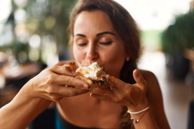 Young woman eating Italian thick tomato pizza with burata cheese