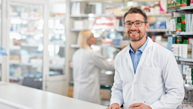 Portrait of happy pharmacist man with pharmacy services, medicine advice and product trust at shop, retail counter