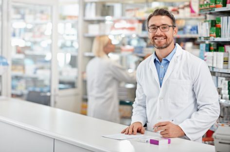 Portrait of happy pharmacist man with pharmacy services, medicine advice and product trust at shop, retail counter