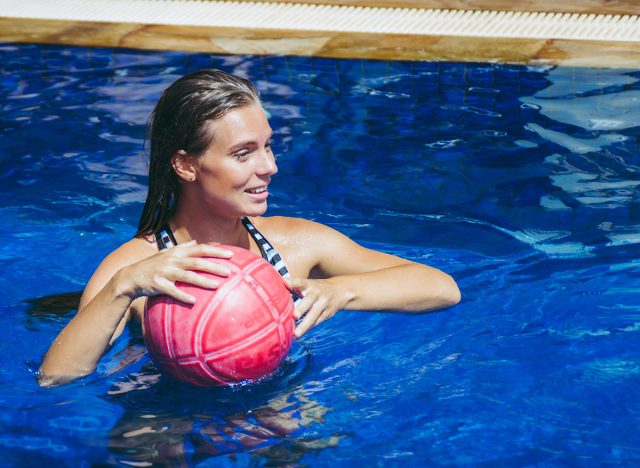 Beautiful woman is playing the ball in swimming pool