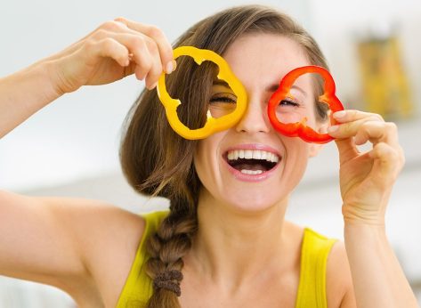 Funny young woman showing slices of bell pepper