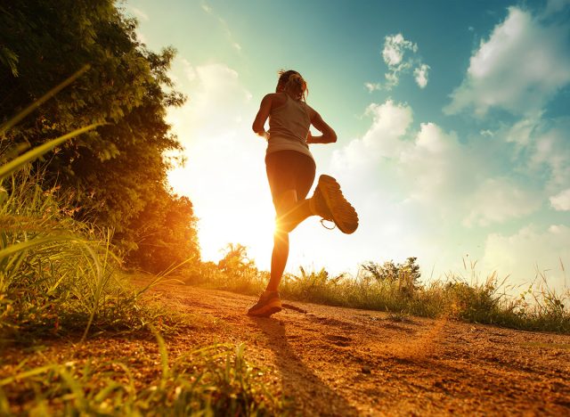 Young lady running on a rural road during sunset