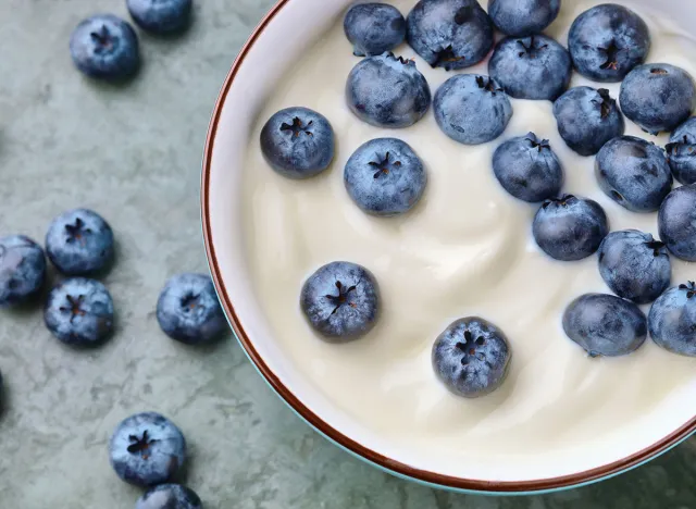 Bowl with yogurt and blueberries on table, top view