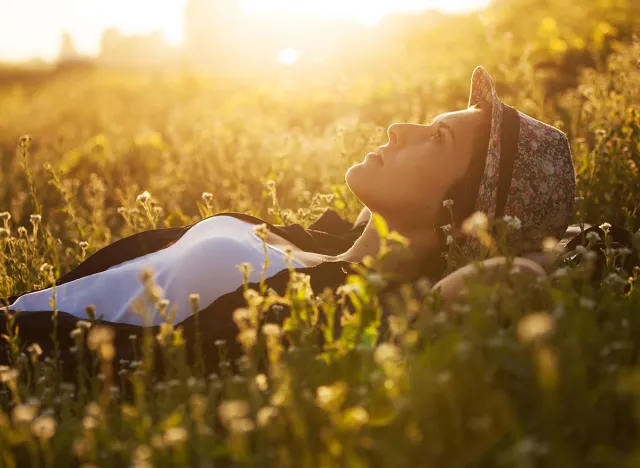 Happy girl lies among the wild flowers on a summer evening