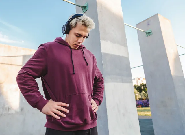 Sportsman warms up, doing neck rotation exercises and listening to music in headphones