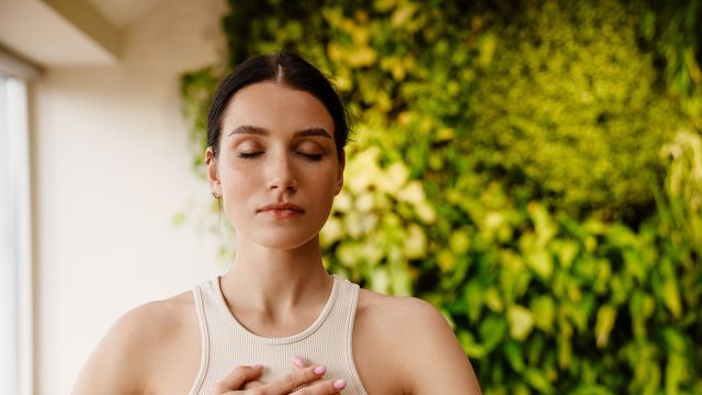 Young white woman doing breathing practice during meditation indoors