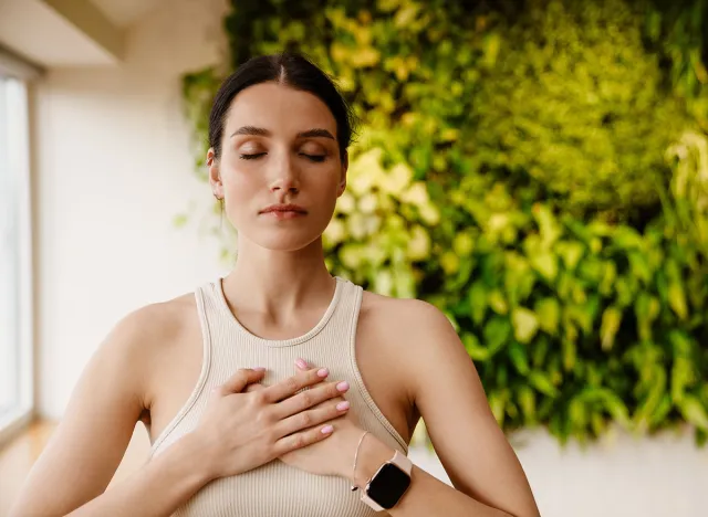 Young white woman doing breathing practice during meditation indoors