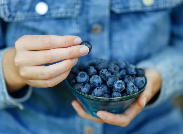 Woman eating ripe blueberries, healthy berries.