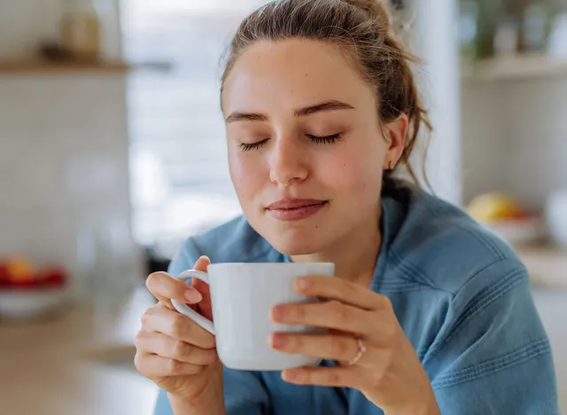 Young woman enjoying cup of coffee at morning, in her kitchen.