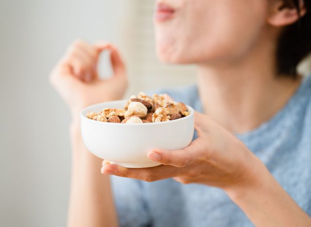 Eating and drinking image of a young woman eating mixed nuts