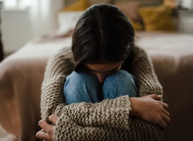 Teenage girl sitting on the floor with head on her knees, koncept of mental health.