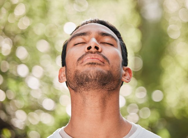 Man, breathing and relax with peace in nature for exercise, workout or meditation for zen after fitness for spiritual wellness. Calm, athlete and freedom in environment and training mindfulness