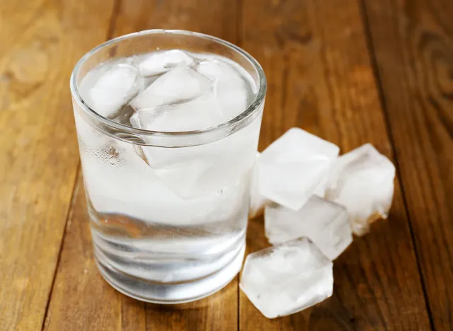 Summer cocktail with ice cubes on wooden table