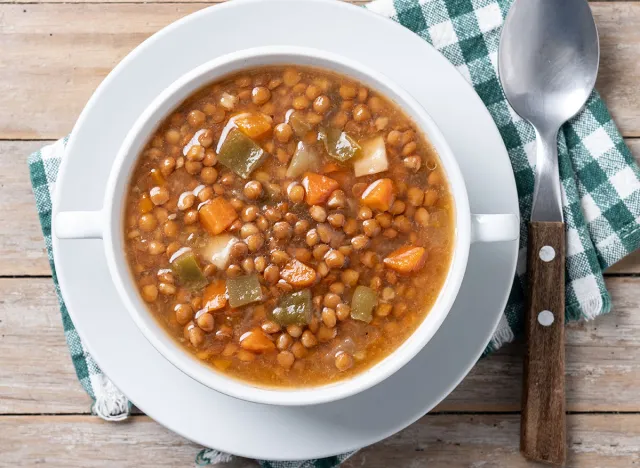 Lentil soup with vegetables in bowl on wooden table. Top view