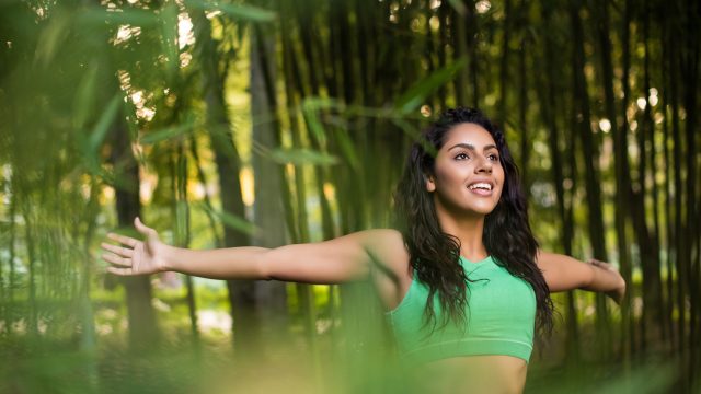 Woman,Stretching,Her,Arms,In,Bamboo,Garden