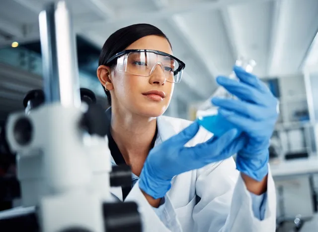 Woman, beaker or scientist in laboratory for science innovation, life expectancy or antiaging medicine. Futuristic, medical or healthcare biologist with chemistry liquid in research or examination