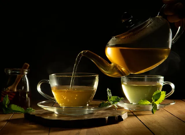 Close up of green tea being poured from teapot into cup