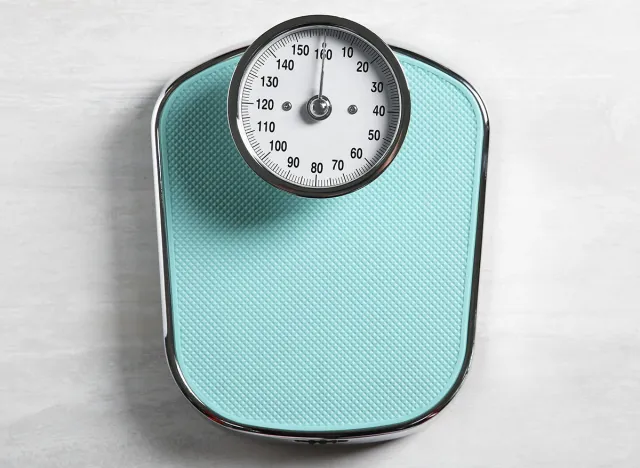 One bathroom scale on white wooden background, top view