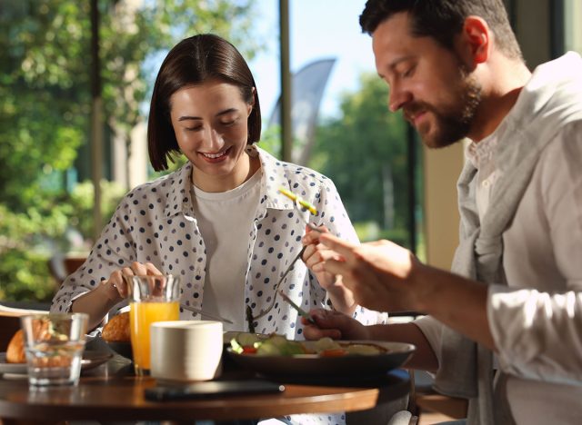 Happy couple having tasty breakfast in cafe