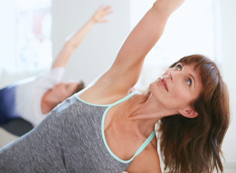 Portrait of mature woman practicing yoga at gym. Fitness female doing Triangle yoga Pose, Trikonasana.