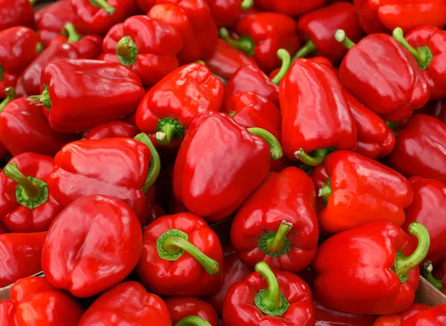 Red bell peppers on a counter in the supermarket. A large number of red peppers in a pile