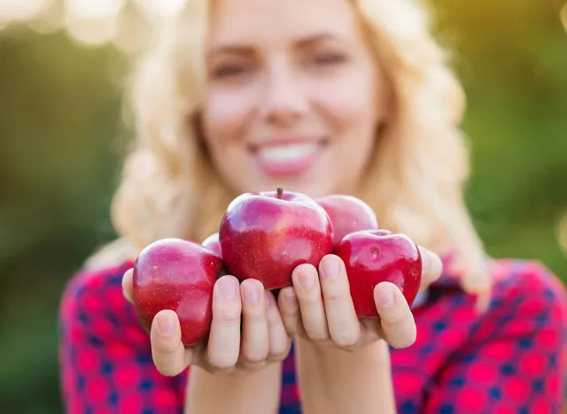 Beautiful woman harvesting apples, eating them