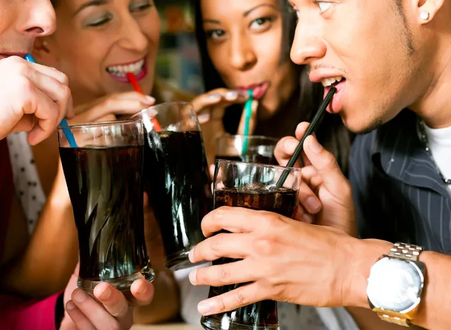 Four friends drinking soda in a bar with colorful straws