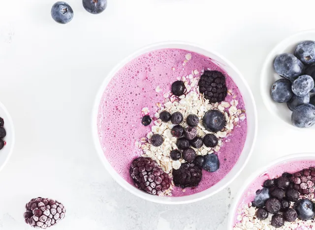 Breakfast with muesli, acai blueberry smoothie, fruits on white background. Healthy food concept. Flat lay, top view, close up