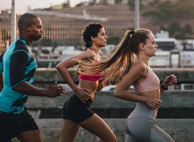 Group of runners in fitness clothing running in the city. Young men and women running together in morning.