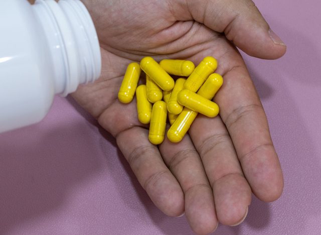 Hands holding yellow capsules, curcuma, berberine.