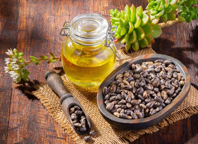 Castor grains and oil on the table, close-up image