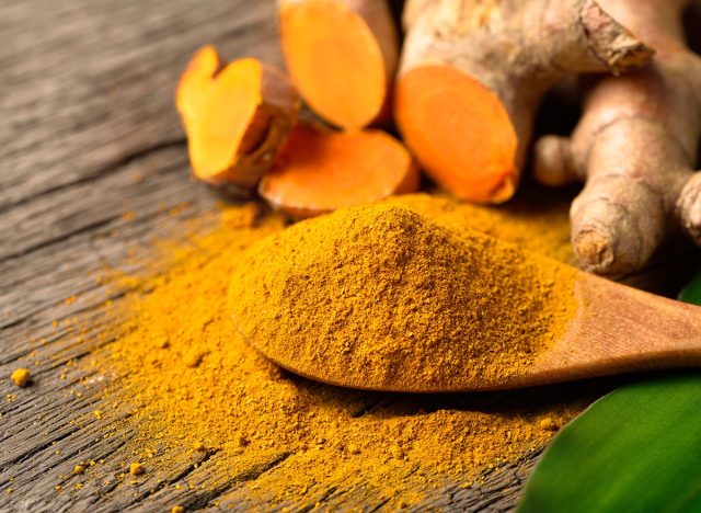 Close-up,Turmeric,(curcumin),Powder,In,Wooden,Spoon,With,Fresh,Rhizome