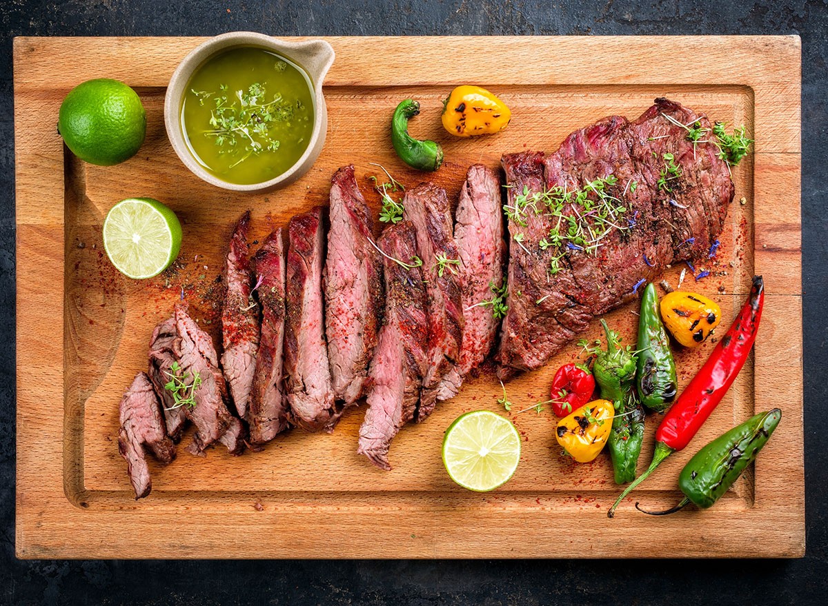 Modern design barbecue dry aged wagyu bavette de flanchet steak with chili and chimichurri sauce as top view on a wooden cutting board