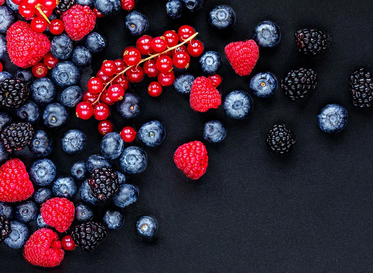 Various fresh forest berries on black stone background, top view. Berry mix. Flat lay. blueberries, raspberry, raspberries, blackberries, berry