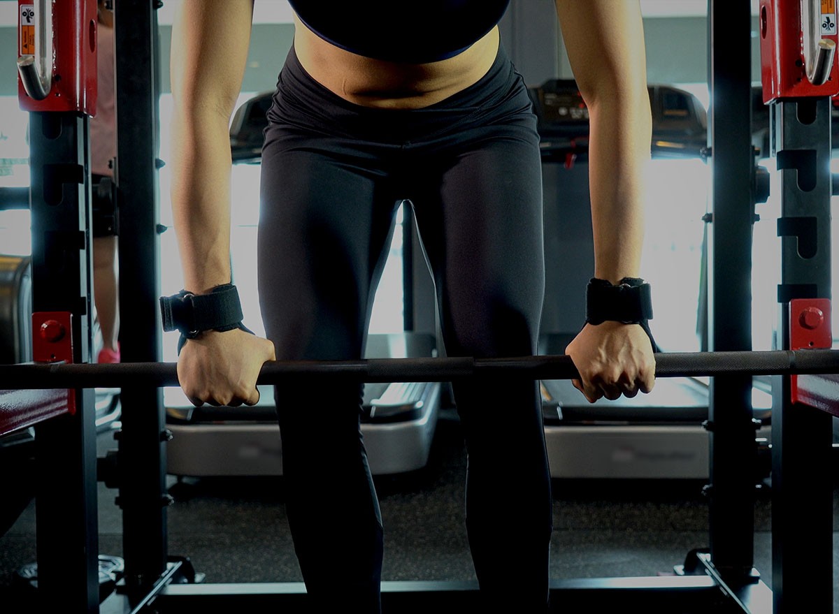 Close up legs of sport woman standing and preparation to lifting weight or pull ups for exercise in fitness gym, fitness and healthy concept