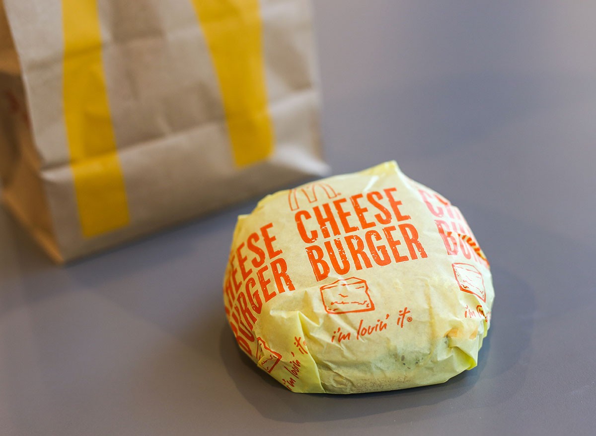 Thailand-April2019: Cheeseburger with yellow paper wrap for take home is a hamburger sold by McDonald's. The cheeseburger is a burger similar to a regular hamburger, but with a slice of cheese added u
