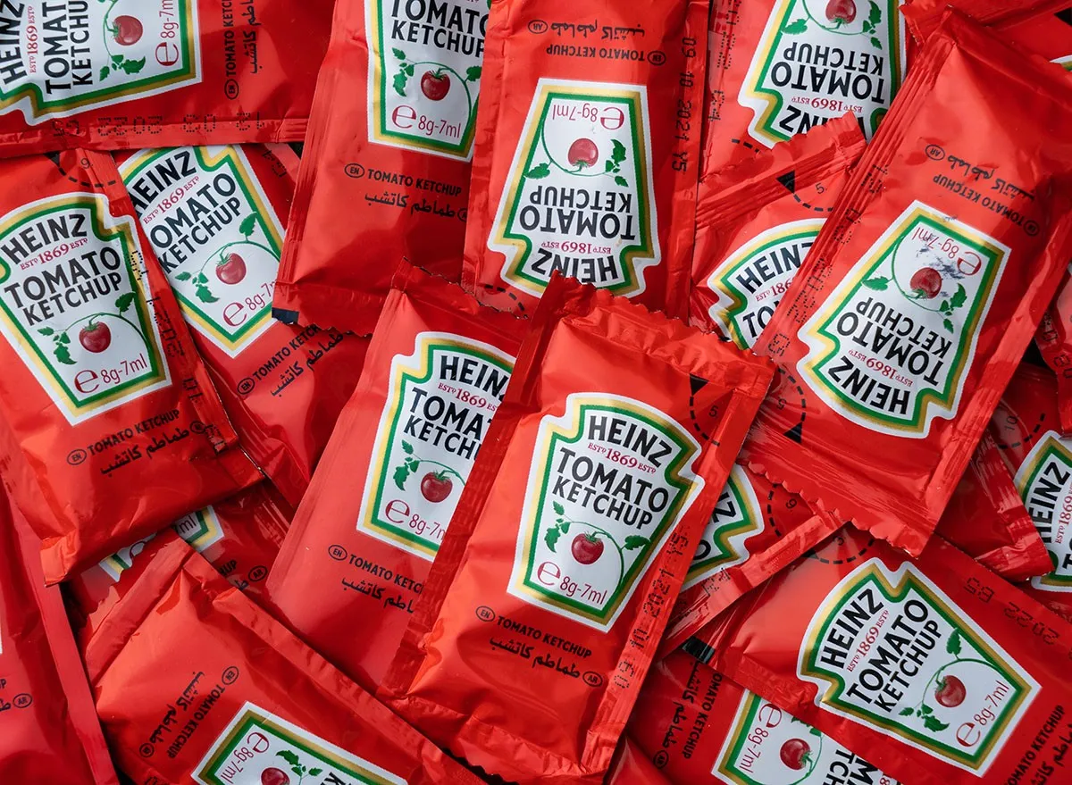 Packets of single serving Heinz Tomato Ketchup on wooden background. mcdonalds condiments, sauce