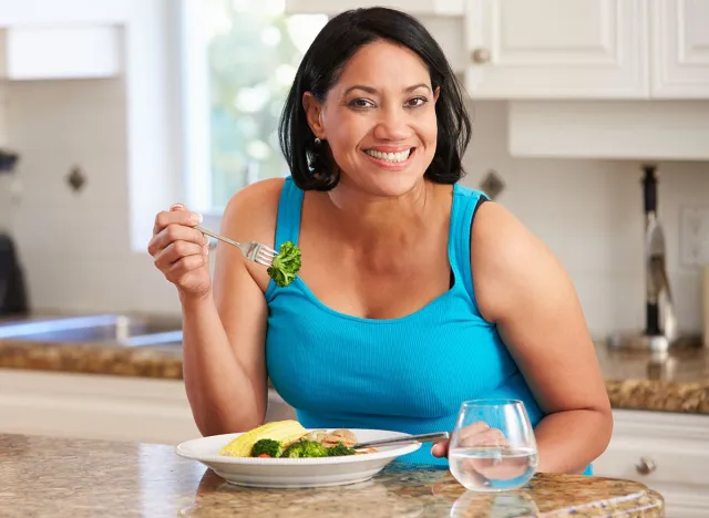 Overweight,Woman,Eating,Healthy,Meal,In,Kitchen