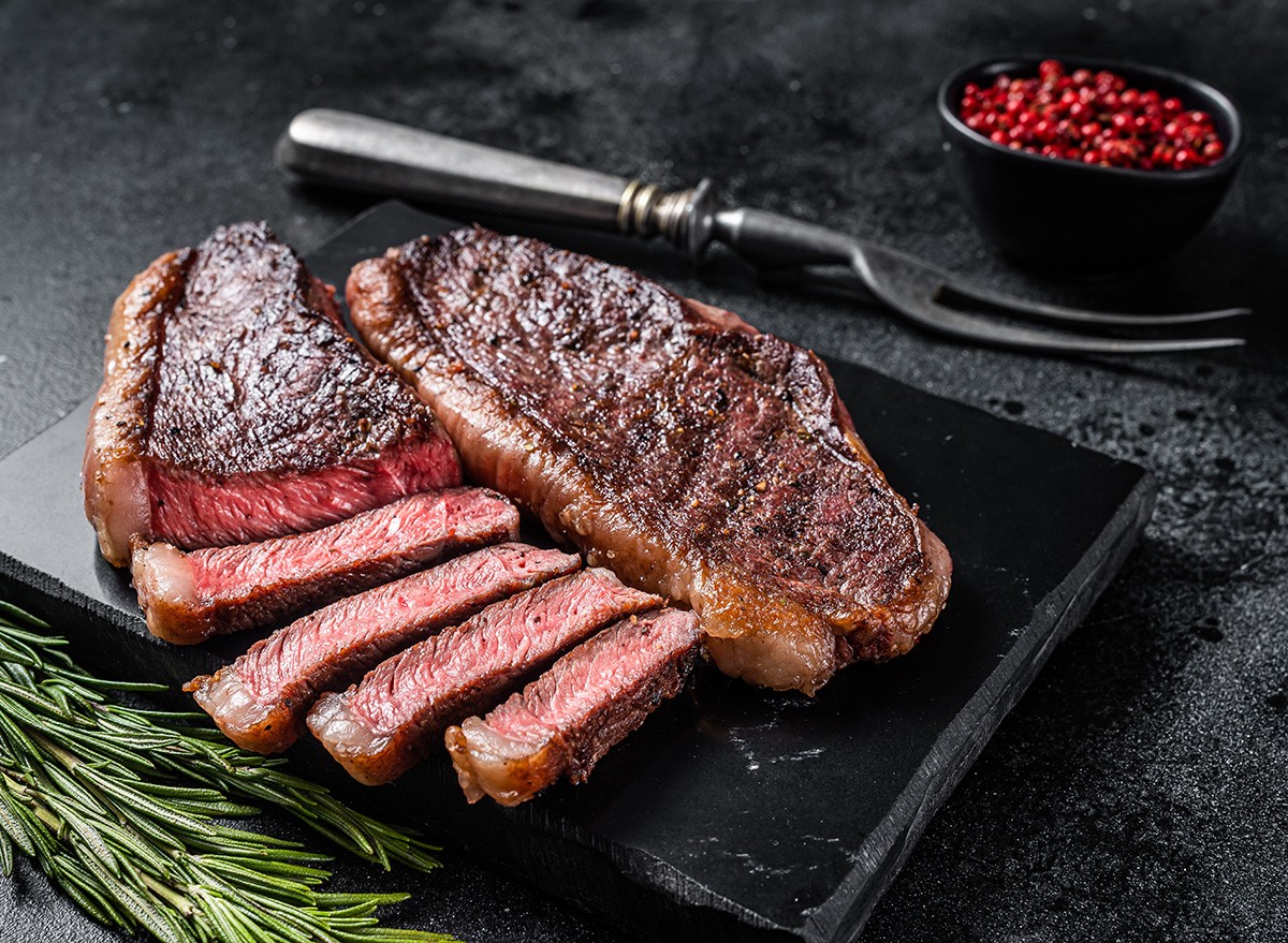 Grilled top sirloin or cup rump beef meat steak on marble board. Black background. Top view