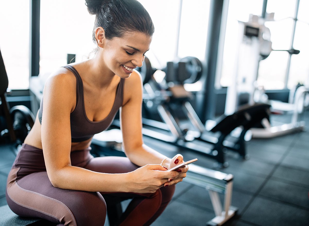 Portrait of sport woman using mobile after exercise at gym.