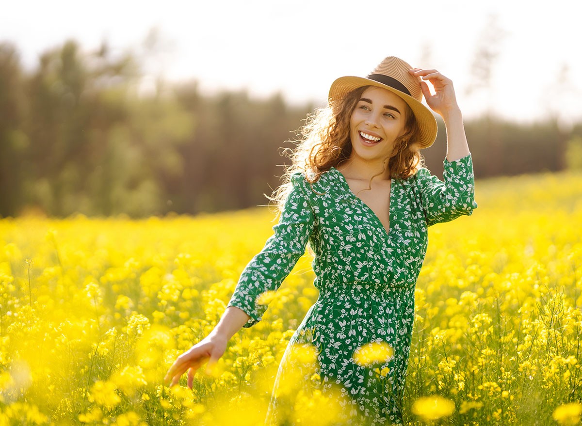 Happy woman in bright dress in rapeseed field. Nature, vacation, relax and lifestyle. Summer landscape.