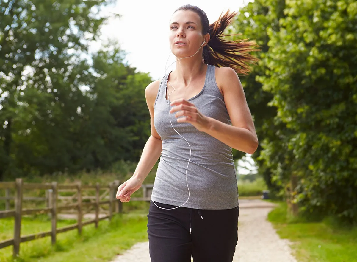 Woman Running In Countryside Wearing Earphones